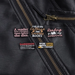 Detailed close-up of five coffee and reading enamel pins on a black leather jacket texture