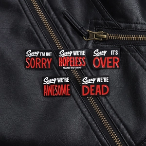 Cinq broches en émail noir avec citations ironiques sur une veste en cuir noir texturé