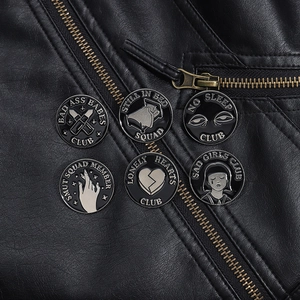 Detail of creative black and white enamel pins on black leather jacket with punk badges