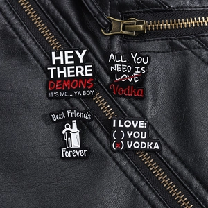 Close-up of four metal enamel pins with funny phrases on black leather jacket texture