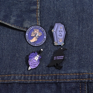 Detailed view of Gothic punk enamel pins including coffin and raven designs on denim jacket