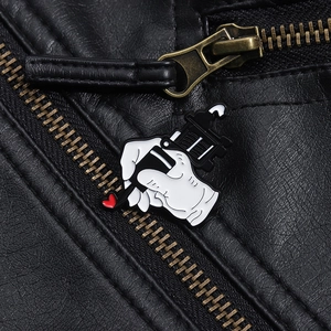 Close-up of tattoo machine enamel pin with red heart on a black leather jacket