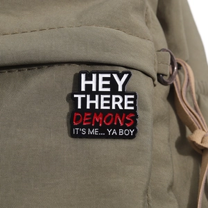 Close-up of Best Friends enamel pin with text on a green canvas backpack