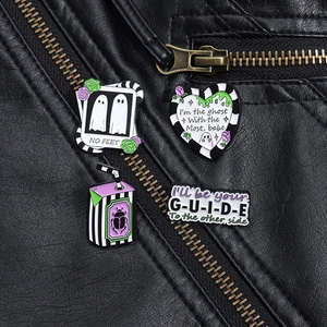 Detail of Beetlejuice theme enamel pins on black leather jacket with gothic aesthetic