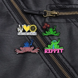 Detailed close-up of set of four colorful frog and floral enamel pins on black leather