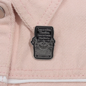 Close-up of Edgar Allan Poe quote on black typewriter enamel pin on denim jacket