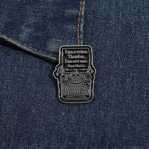 Detail of vintage typewriter enamel pin with literary quote pinned on denim fabric