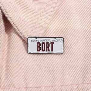 Macro shot of Bort license plate enamel pin on pink denim fabric with detailed metal texture