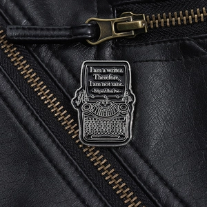 Detail of vintage typewriter enamel pin with Edgar Allan Poe quote on black leather jacket