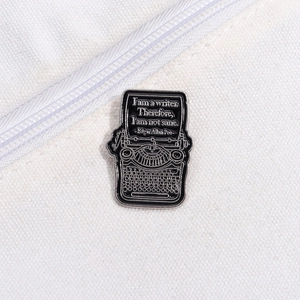 Close-up of a typewriter enamel pin with literary quotes attached to a white canvas bag