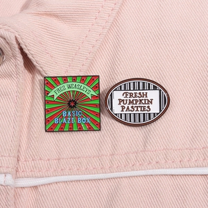 Detail of colorful enamel pins on pink denim fabric featuring creative typography
