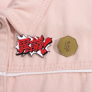 Close-up of Ace Attorney enamel pins with red burst and gold seal on denim jacket