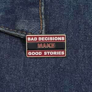 Macro shot of rectangular enamel pin with gold text on a blue denim background
