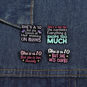 Detailed close-up of four humorous enamel quote pins pinned on blue denim fabric