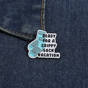 Detail of blue grippy sock enamel pin displayed on a denim jacket pocket surface