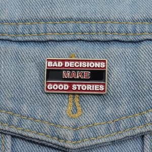 Detail showing the 'BAD DECISIONS MAKE GOOD STORIES' enamel pin on a denim jacket pocket