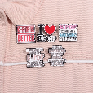 Set of five colorful K-pop enamel pins featuring music slogans on pink denim fabric
