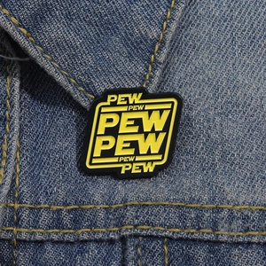 Detail view of a black and yellow enamel PEW PEW pin on blue denim fabric texture
