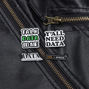 Close-up of four enamel data-themed badges pinned on a black leather jacket with zipper