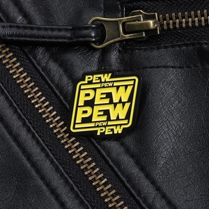 Close-up of Pew Pew Pew enamel pin in sci-fi style attached to black leather jacket