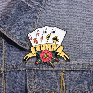 Detailaufnahme einer Vintage-Emaille-Brosche mit Pokerkarten und Lucky-Schriftzug auf Denim