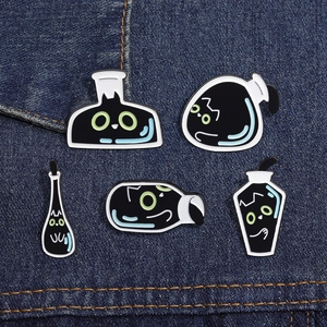 Detailed close-up of 5 black cat enamel pins on blue denim, featuring potion bottle designs