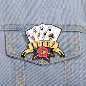 Detail einer Vintage-Emaille-Brosche mit Pokerkarten und Rose auf einer Jeansjacke