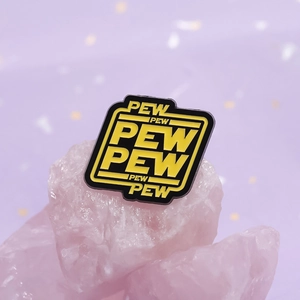 Macro shot of an enamel 'PEW PEW' brooch placed on a pink crystal stone background