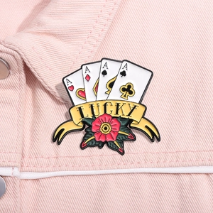 Detail der kreativen Metallbrosche mit Spielkarten, Lucky-Band und Rose auf rosa Jeansstoff