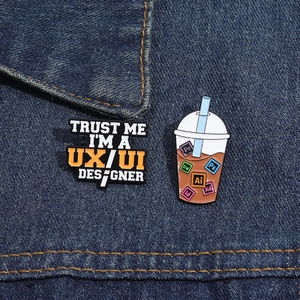 Détail de pin's en émail pour designer avec texte UX/UI et icônes logiciels sur denim