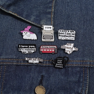 Détail d'un ensemble de pins émaillés album TTPD sur fond de tissu denim bleu