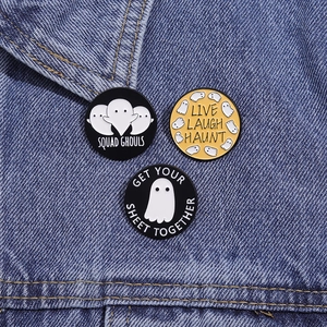 Drei Geister-Emaille-Pins mit lustigen Wortspielen auf dunkelblauem Denim-Hintergrund
