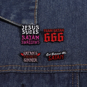 Close-up of four rebel subculture enamel pins featuring Satanic themes on blue denim cloth