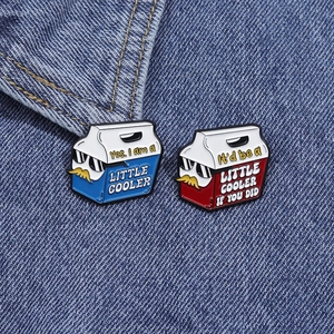 Détail de pins de glacière en émail rouge et bleu avec motifs drôles sur tissu denim