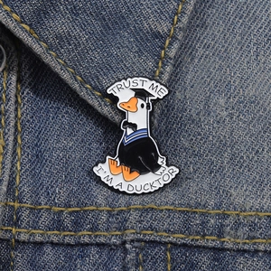Detail of Trust Me I'm a Ducktor enamel pin featuring a cartoon duck in graduation gown