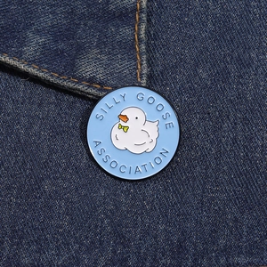 Round enamel pin featuring a cartoon silly goose on blue denim fabric background