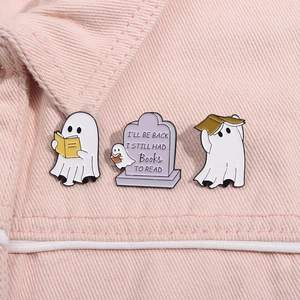Detailed close-up of ghost enamel pins with reading theme on pink denim fabric surface