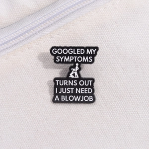 Close-up of black enamel brooch with funny adult quote on white canvas background
