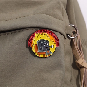 Detail of Everything is under control enamel pin attached to a green canvas backpack