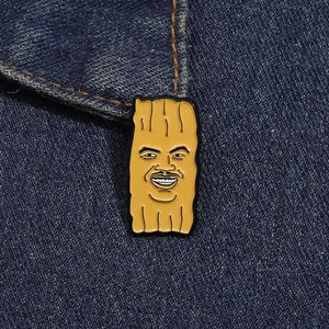 Gros plan d'un badge émaillé jaune rigolo sur un fond en tissu denim bleu foncé