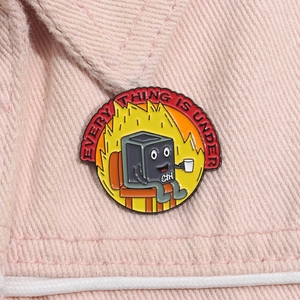 Macro detail of a round enamel pin with a Ctrl character pinned on pink denim fabric