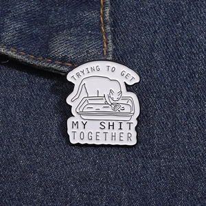 Gros plan détaillé d'un pin's chat en émail sur denim avec un texte humoristique