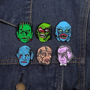 Detailed view of six classic horror monster enamel pins pinned on a denim jacket surface