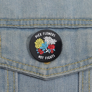 Detail view of Pick Flowers Not Fights enamel pin on light blue denim jacket pocket