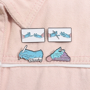 Detailansicht der medizinischen Emaille-Broschen mit Skalpell und Spritze auf rosa Denim