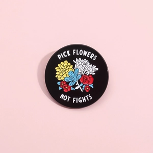Black enamel round brooch with floral design and Pick Flowers Not Fights slogan