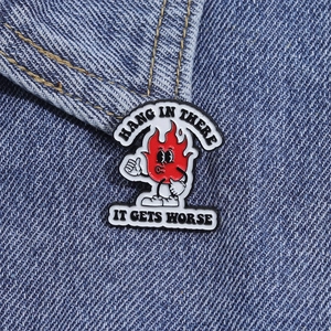 Détail du pin's émaillé flamme rouge avec texte sur tissu en denim bleu foncé