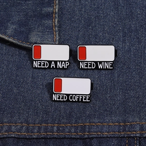 Detailed view of battery level enamel pins with text Need a Nap and Need Wine on denim