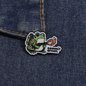 Détail de l'épinglette grenouille émaillée avec texte sur texture en denim bleu foncé