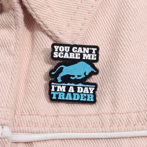Détail de la broche émaillée You Can't Scare Me I'm a Day Trader sur du denim rose